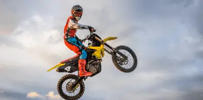 Motocross rider performing a jump on a yellow dirt bike against a dramatic sky, representing iCREDIT motorcycle loans in New South Wales.