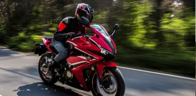 Sportbike rider in red gear speeding along a forested road in Queensland.