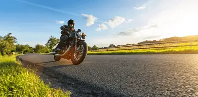 Motorcyclist riding a cruiser bike along a sunny country road in Western Australia.