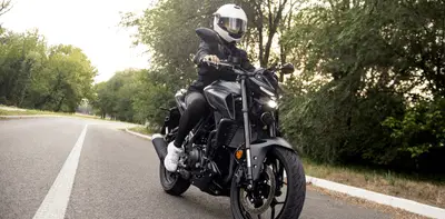 Motorcyclist riding a black bike on a quiet road surrounded by trees in South Australia.