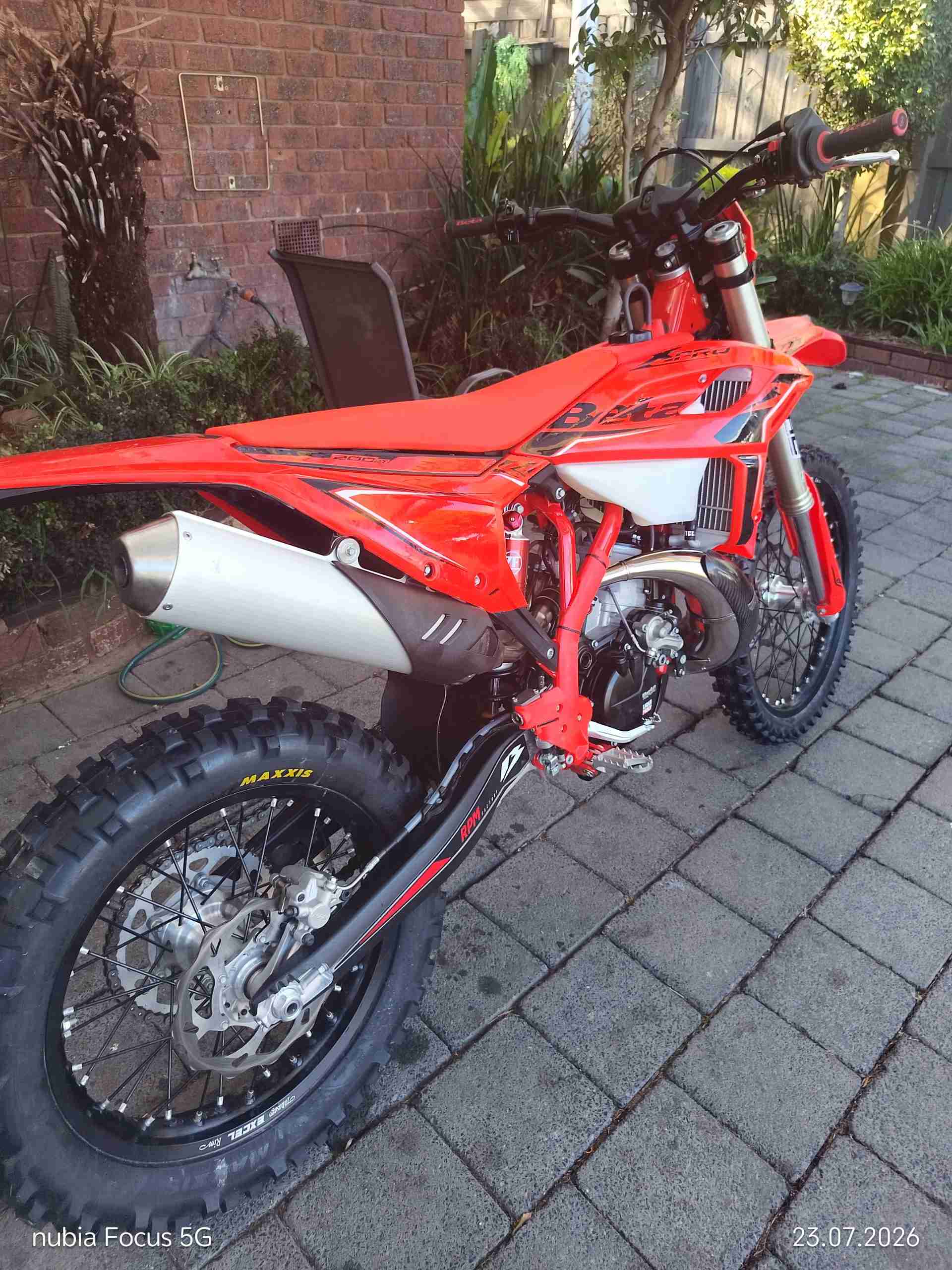Red Beta 200 Motorbike parked outside of a house.