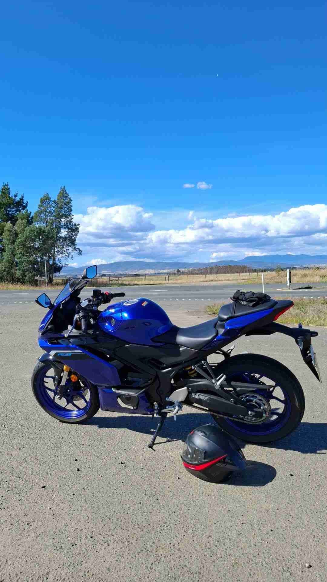 Blue Yamaha YZF motorcycle financed through iCREDIT Motorcycle Loans in Tasmania, parked on a scenic roadside with helmet nearby.